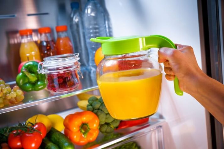 How To Store Smoothies 11 Ways (Fridge, Freezer, How Long); Woman takes the Orange juice from the open refrigerator
