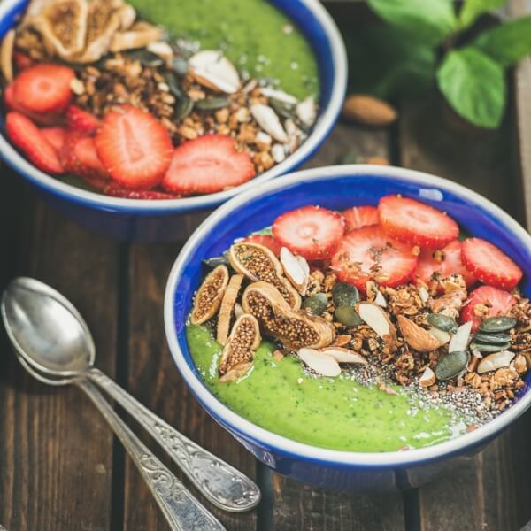 Green smoothie bowls with granola, fruit, nuts