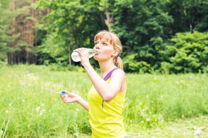 How To Lose Water Weight - 14 Ways To Reduce The Bloat  Young beautiful fit woman drink water after her exercise