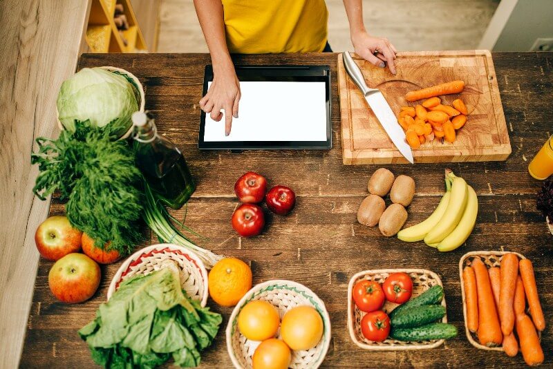 Going Vegan?; Female person cooking on the kitchen, eco food, reading computer