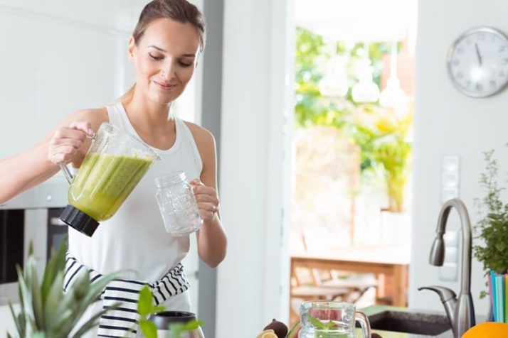 woman pouring smoothie into jar from blender