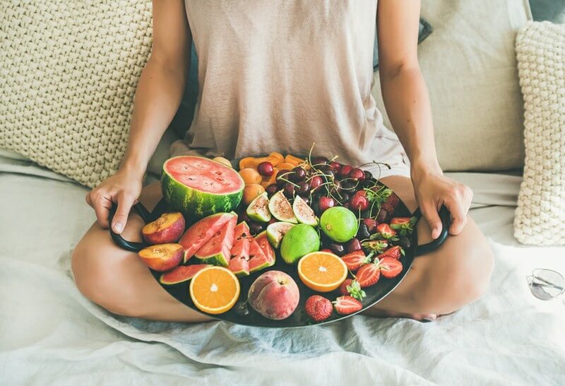 Paleo vs Vegan? Why A Pegan Diet Is Your Best Option; Young girl holding tray full of fresh seasonal fruits