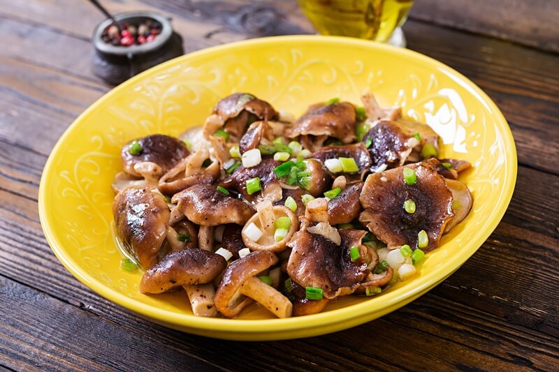 34 High Protein Vegetables You Probably Already Eat; Fried mushrooms shiitake with green onion on wooden background. Chinese food.