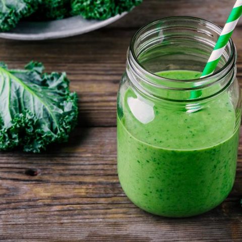 Healthy green smoothie with kale in mason jar on rustic wooden background