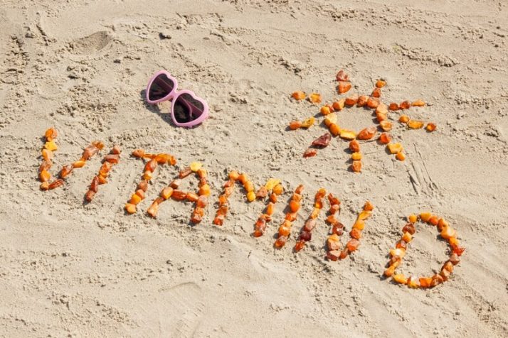 Sunglasses, inscription vitamin D and shape of sun on sand at beach