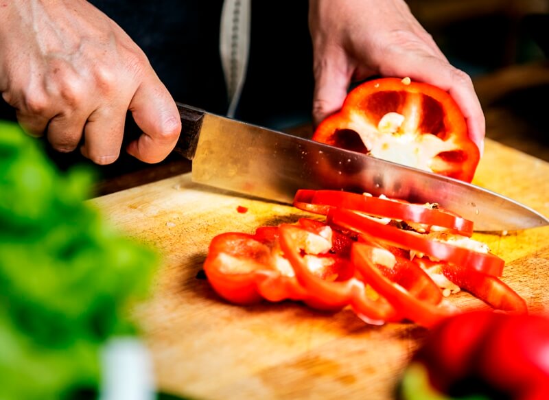 34 High Protein Vegetables You Probably Already Eat; hand with knife cutting bell pepper