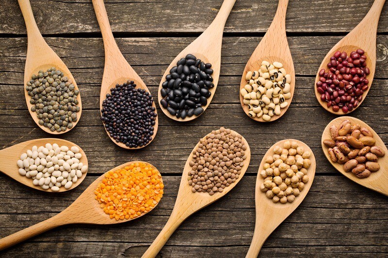 34 High Protein Vegetables You Probably Already Eat; various dried legumes in wooden spoons