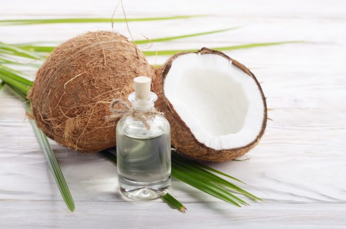 Guide To Fruit: Facts, Benefits, Tutorials, Recipes & Videos; Coconut and oil in glass jar on white wooden table. Care concept