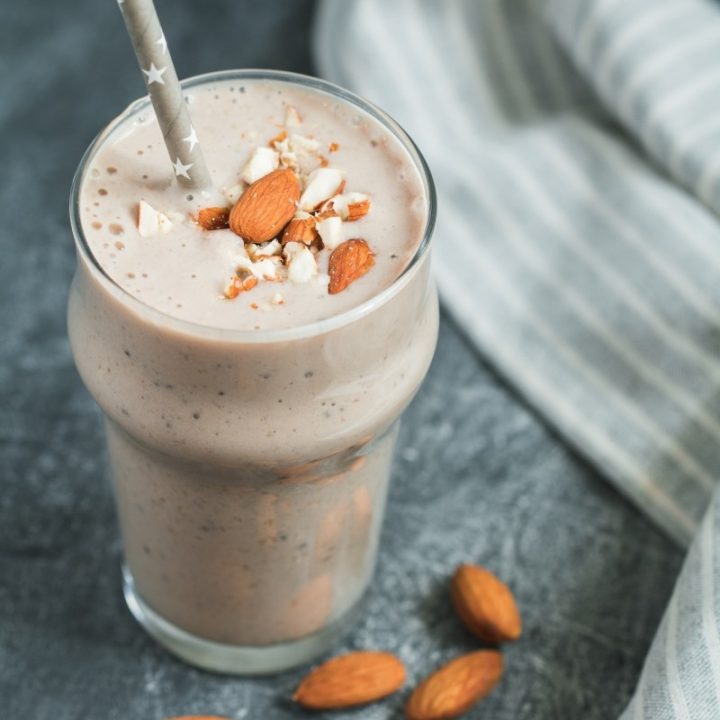 Smoothie with banana, almond and chia seeds over grey textured background.