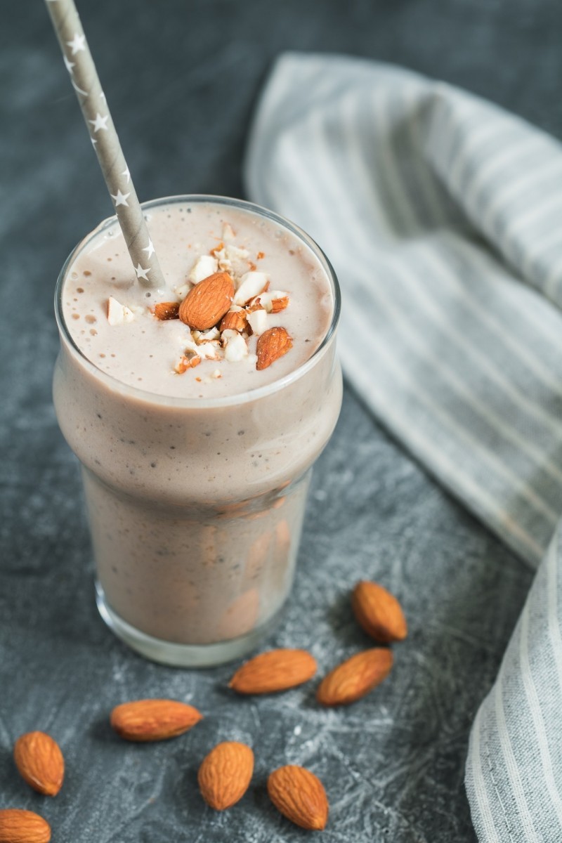 Smoothie with banana, almond and chia seeds over grey textured background.