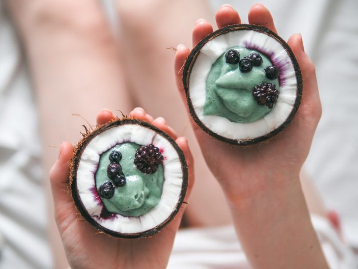 How To Make A Blue Smoothie 3 Ways: With & Without Spirulina ; Two coconut half spirulina smoothie in woman hands