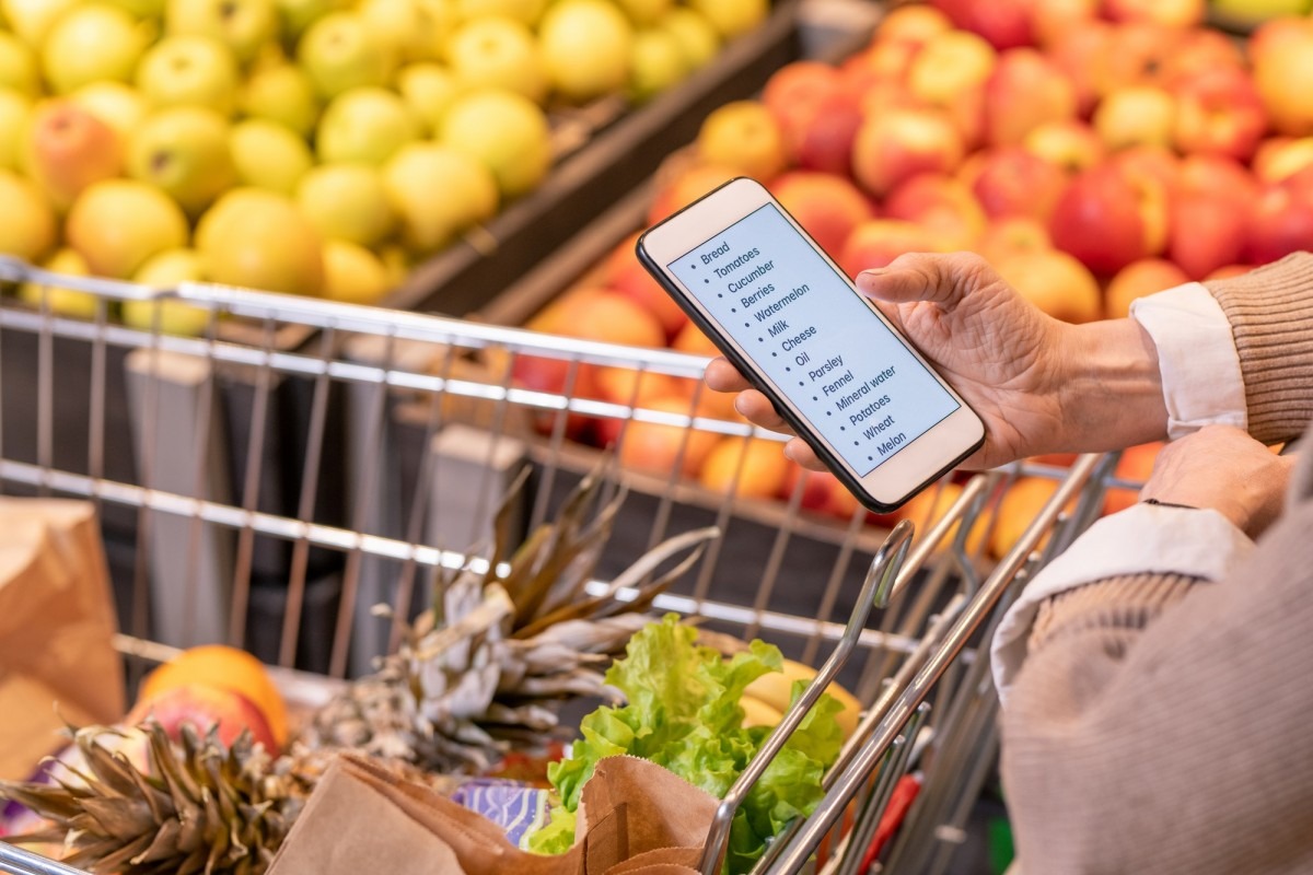 Hands of contemporary aged woman looking through shopping list in smartphone Hands of contemporary aged woman looking through shopping list in smartphone