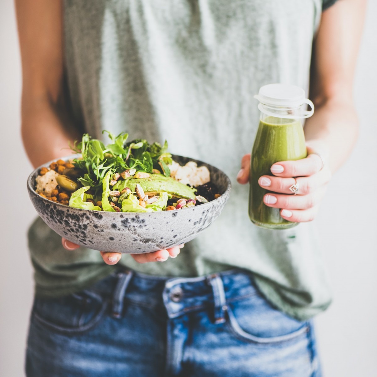 Woman in jeans holding healthy superbowl and smoothie, square crop